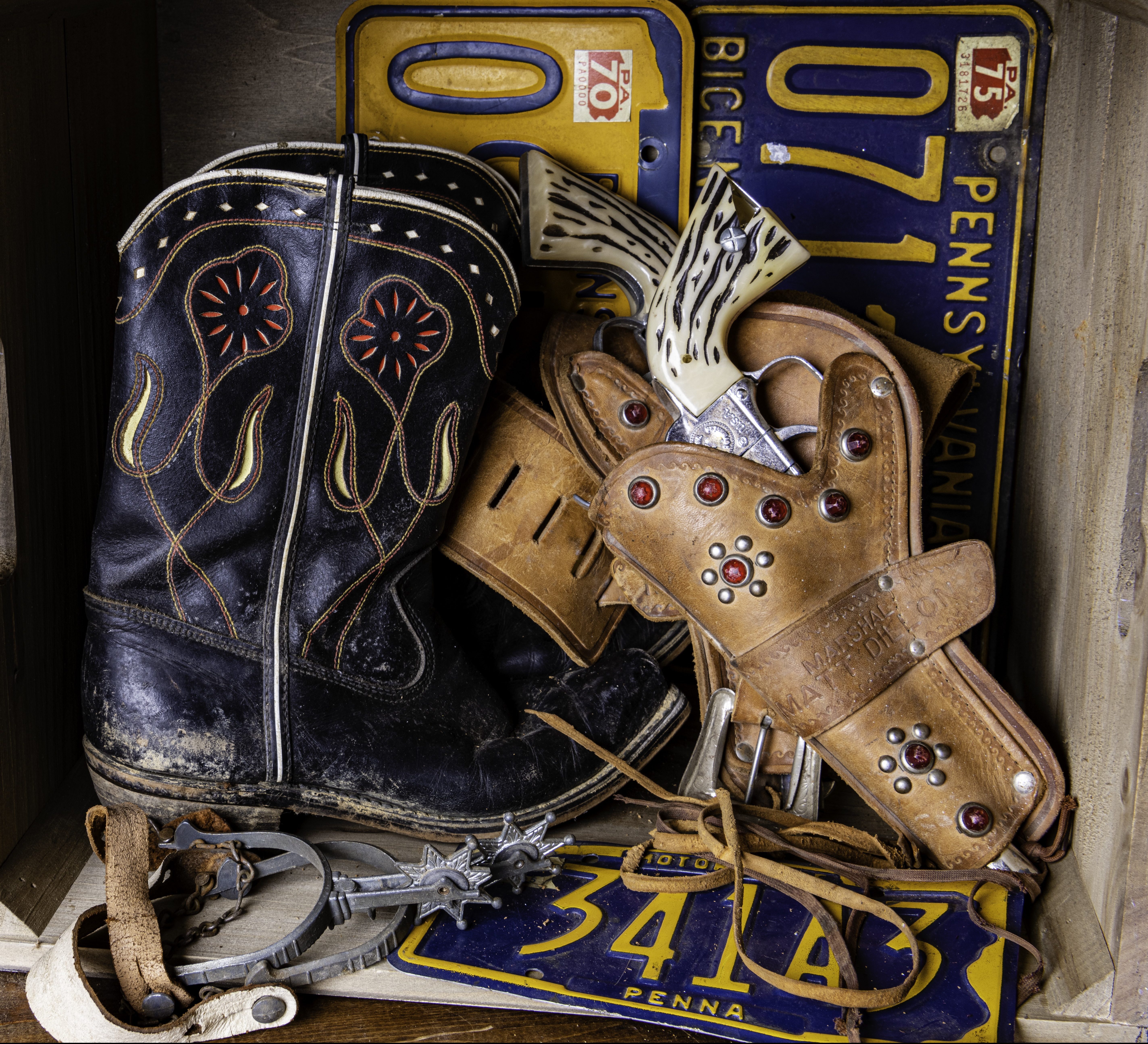 young boys treasure box with vintage cowboy boots and toy guns